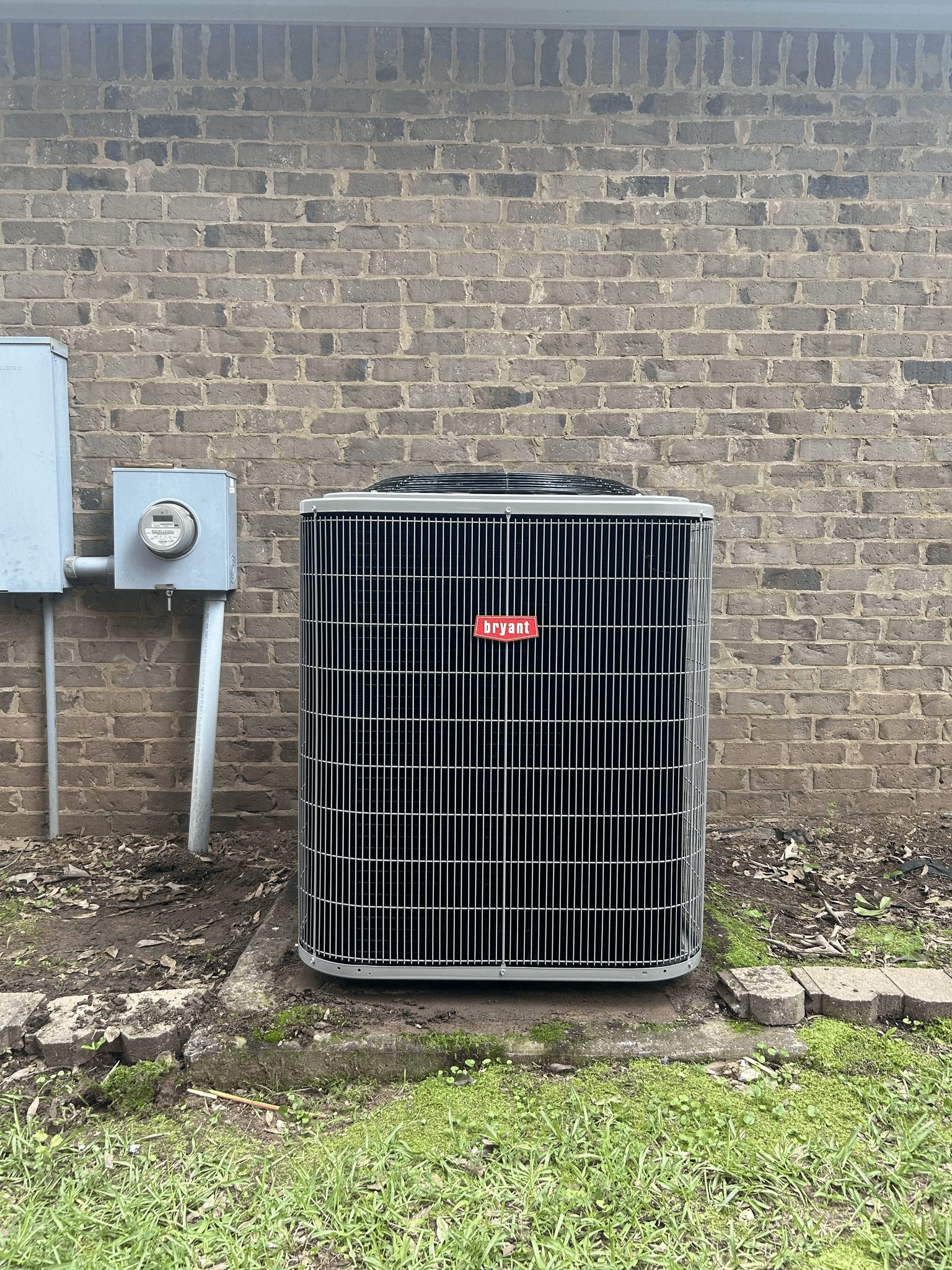 Bryant outdoor air conditioning unit installed beside a brick home
