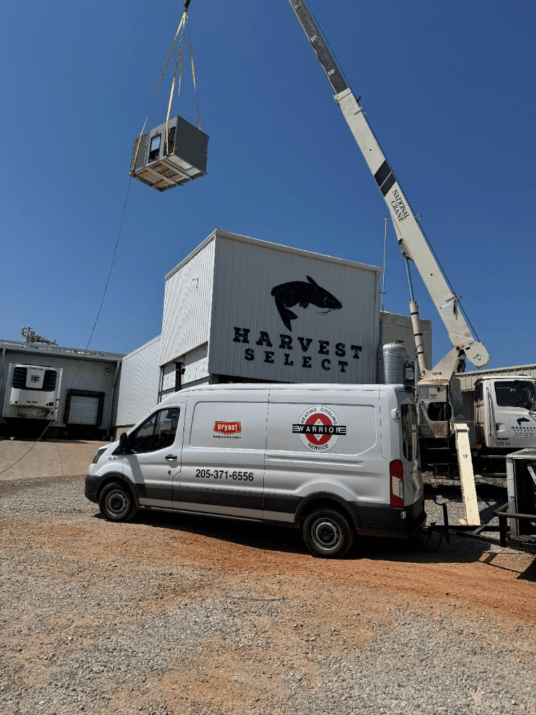 Crane lifting a commercial HVAC unit onto an industrial building roof