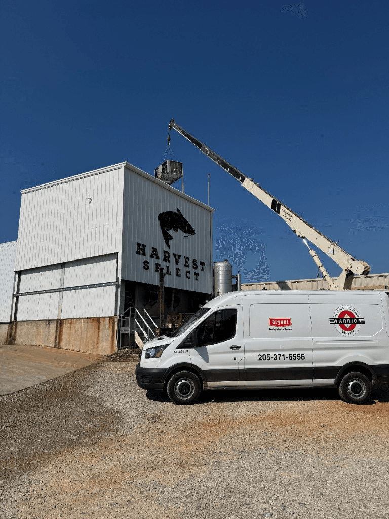Warrior Heating & Cooling service van on site during a commercial rooftop HVAC installation